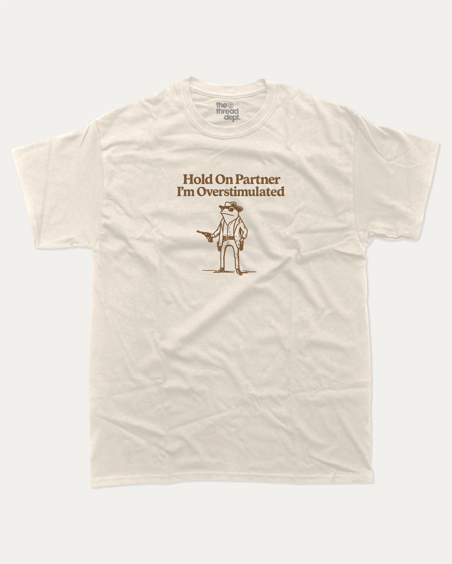Hold On Partner I'm Overstimulated graphic t-shirt, perfect for adults. Funny Frogs tee, trending meme shirt, unique gift idea. Cream.