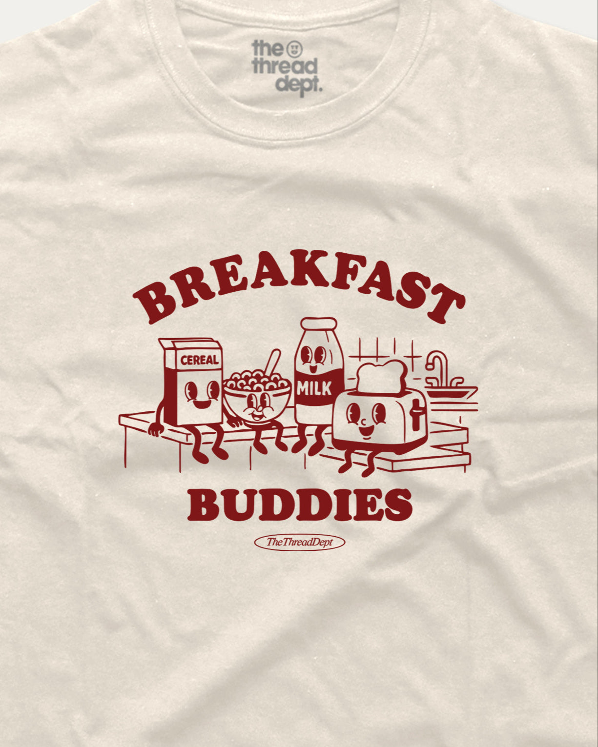 White t-shirt with red 'Breakfast Buddies' graphic featuring cartoon cereal box, milk carton, bowl of cereal, and toaster.