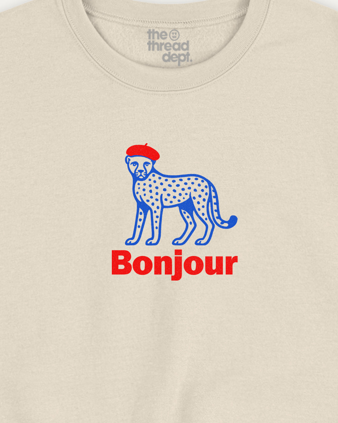 Beige t-shirt with a blue cheetah wearing a red hat and 'Bonjour' text on a beige background.