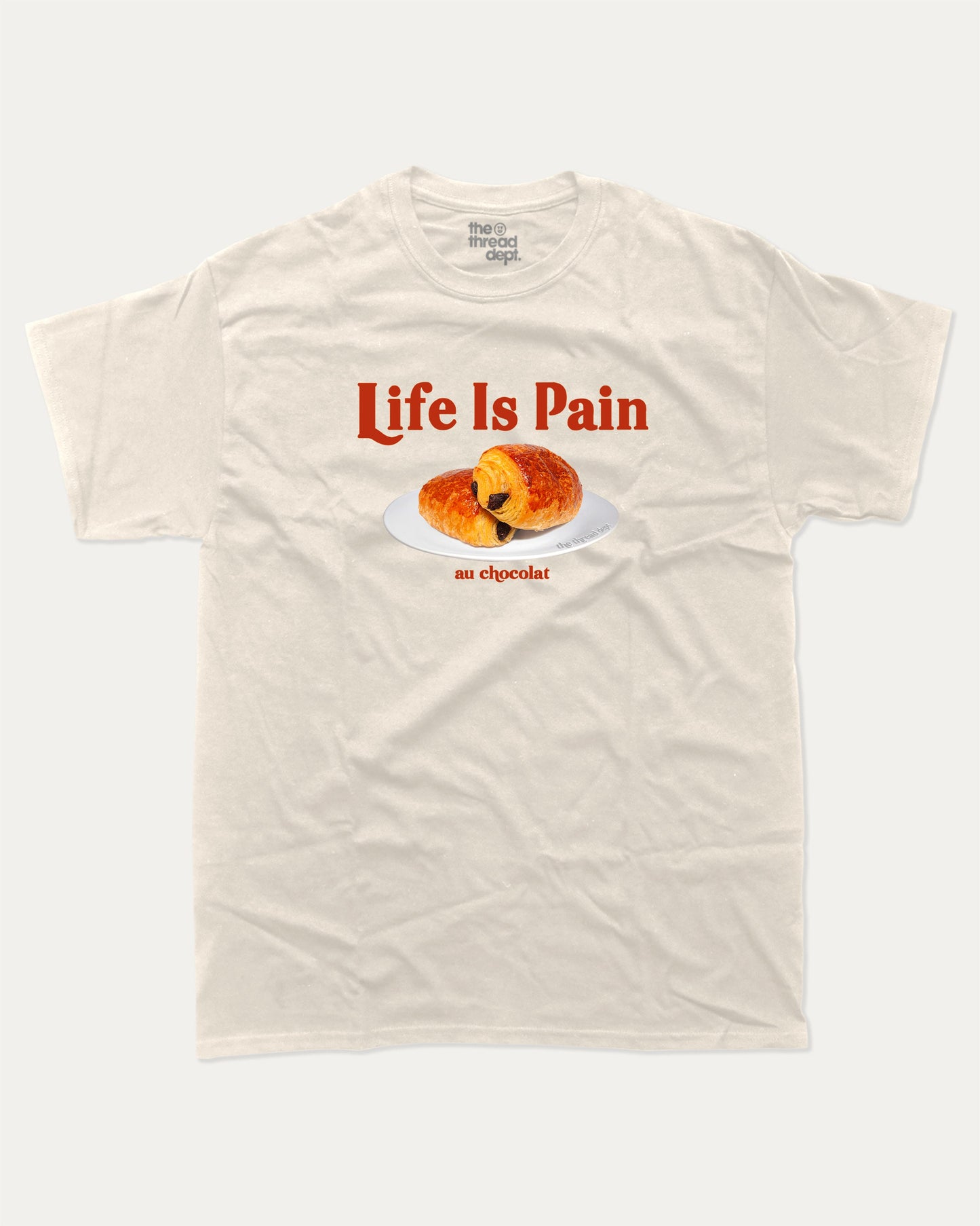 Life Is Pain Au Chocolat graphic t-shirt, perfect for adults. Funny bread tee, trending meme shirt, unique gift idea. Cream.