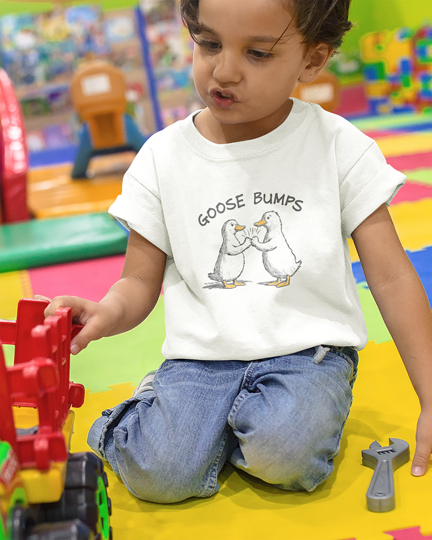Child playing with toys wearing a t-shirt with 'Goose Bumps' design.