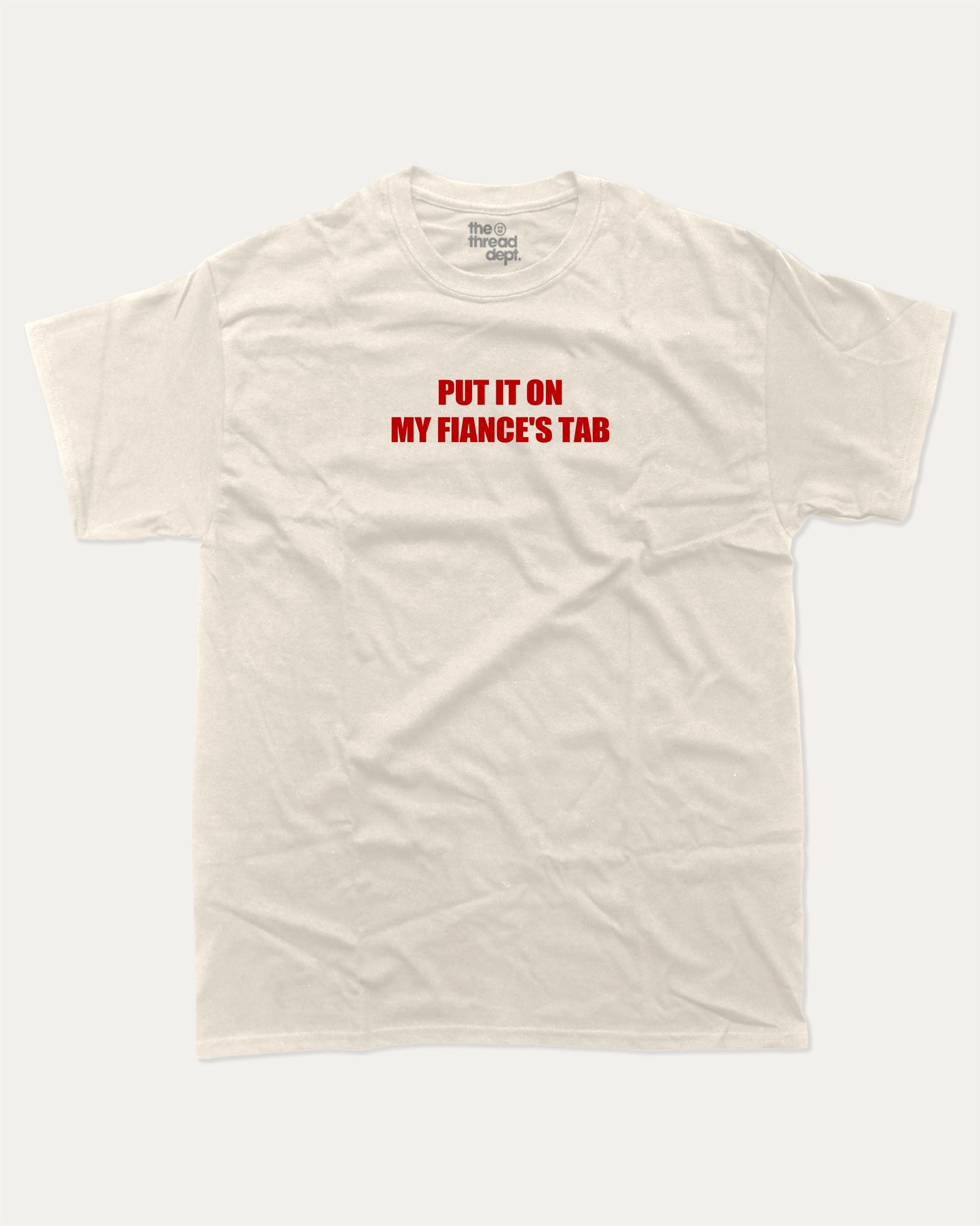 Put It On My Fiance's Tab graphic tee with bold and humorous print, funny and trendy graphic. Perfect for adults and gift-giving. Cream shirt.