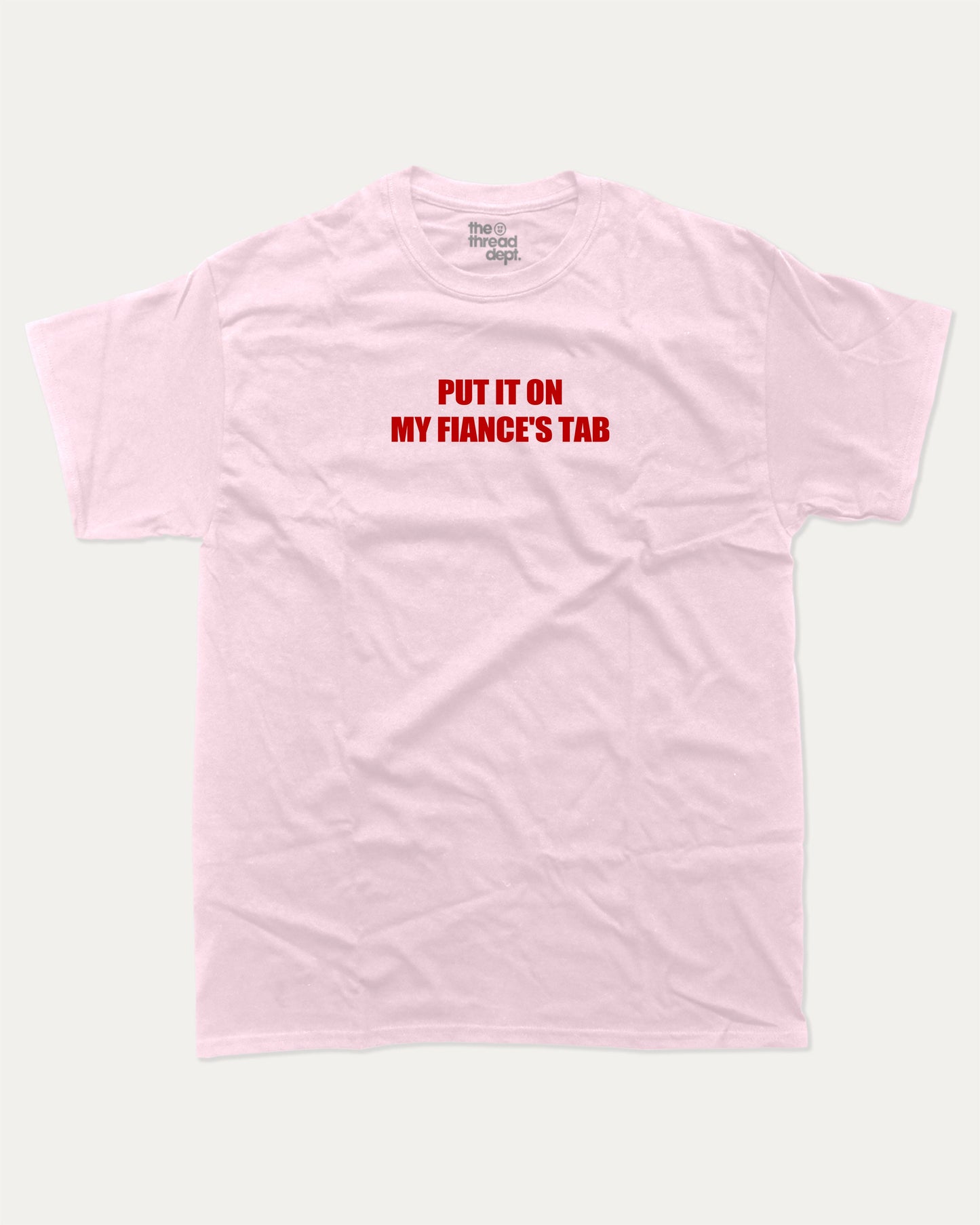 Put It On My Fiance's Tab graphic tee with bold and humorous print, funny and trendy graphic. Perfect for adults and gift-giving. Pink shirt.