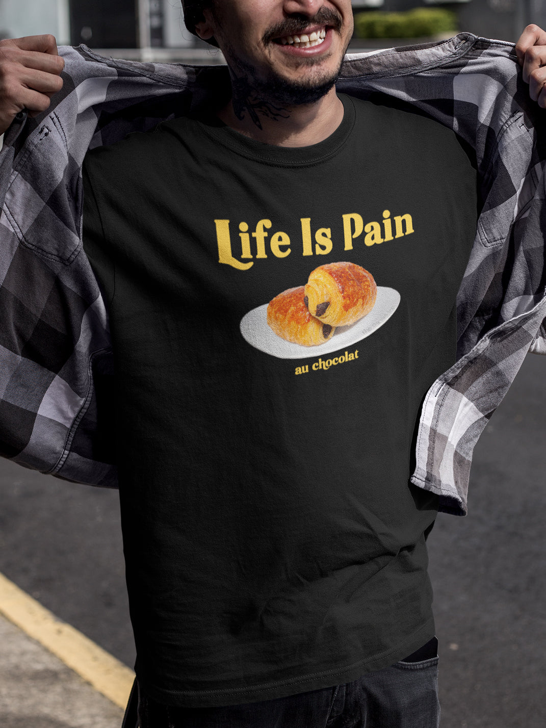Person wearing a black t-shirt with 'Life is Pain' and 'su chocolate' text.