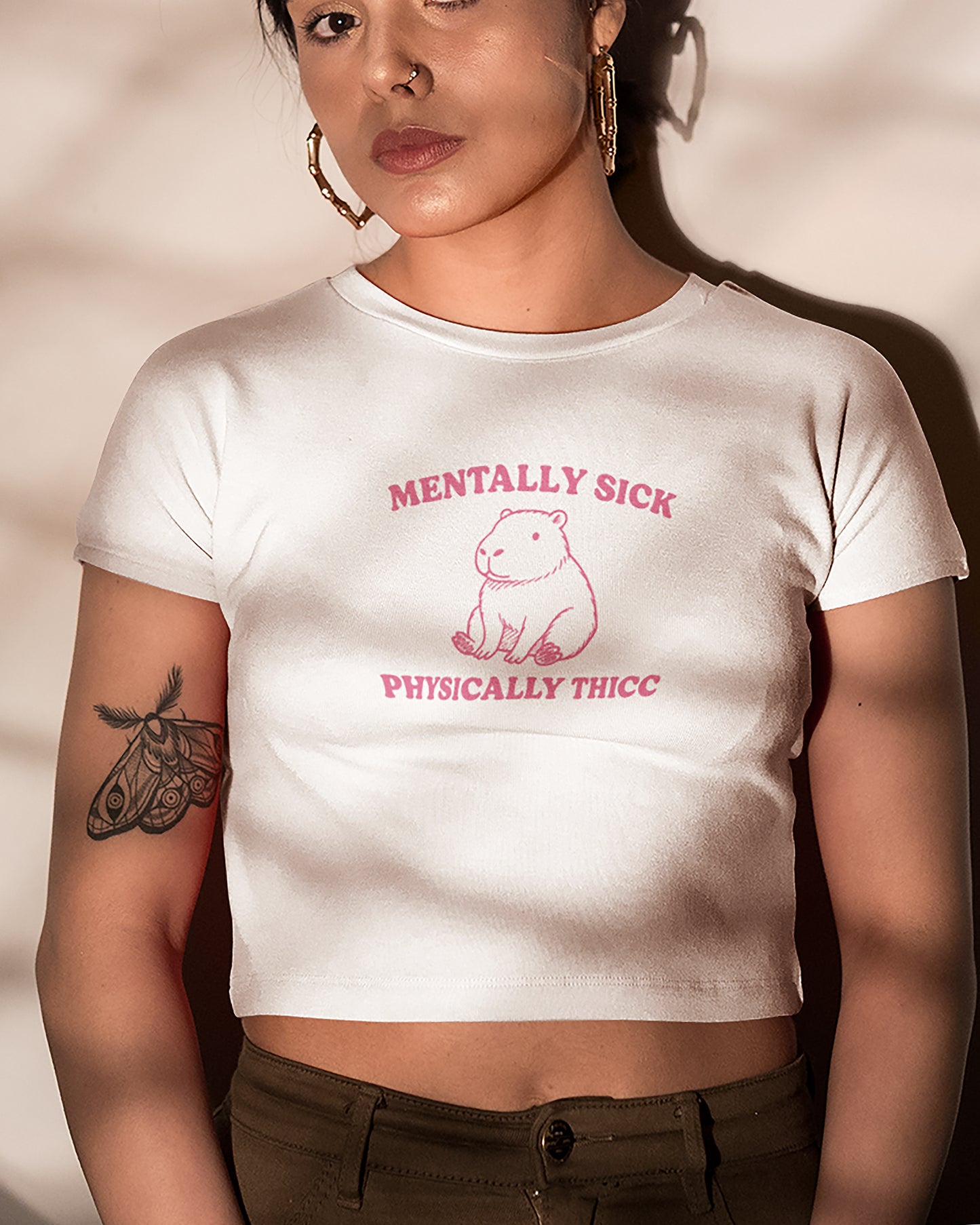 Person wearing a white t-shirt with pink text and graphic design.