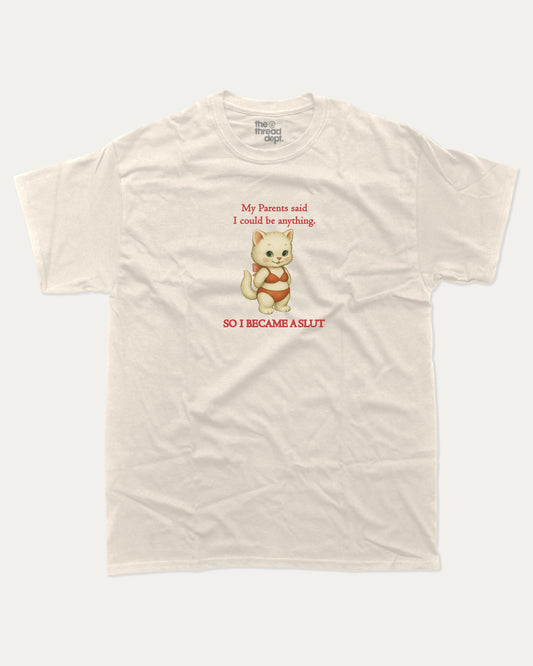 Beige t-shirt with a cartoon cat i became a slut graphic and text on a white background