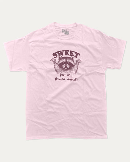 Sweet But Will Throw Hands Raccoon graphic t-shirt, perfect for gifts. Funny raccoon tee, trending meme shirt, unique gift idea. Pink.