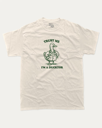 Trust Me I'm A Ducktor graphic t-shirt, perfect for gifts. Funny duck graphic tee, trending meme shirt, unique gift idea. Cream.