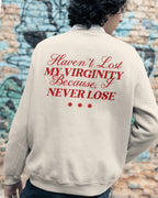 Person wearing a beige sweatshirt with I Never Lose graphic text against a graffiti-covered wall.