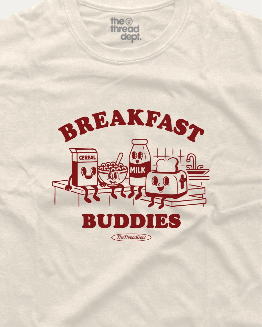 White t-shirt with red 'Breakfast Buddies' graphic featuring cartoon cereal box, milk carton, bowl of cereal, and toaster.