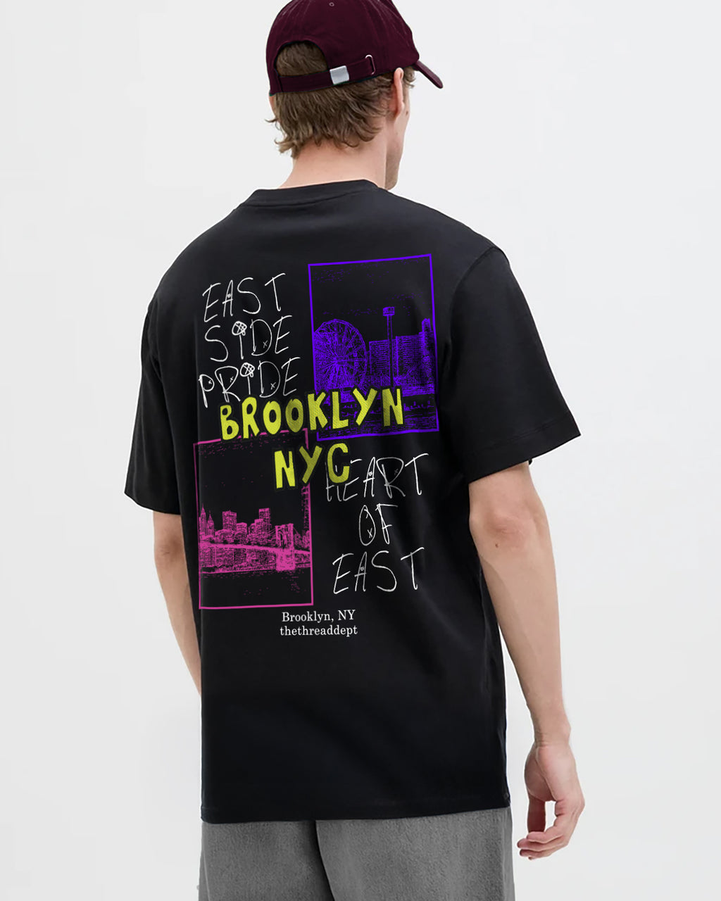 Person wearing a black t-shirt with colorful text and brooklyn nyc graphics on the back, standing against a white background.