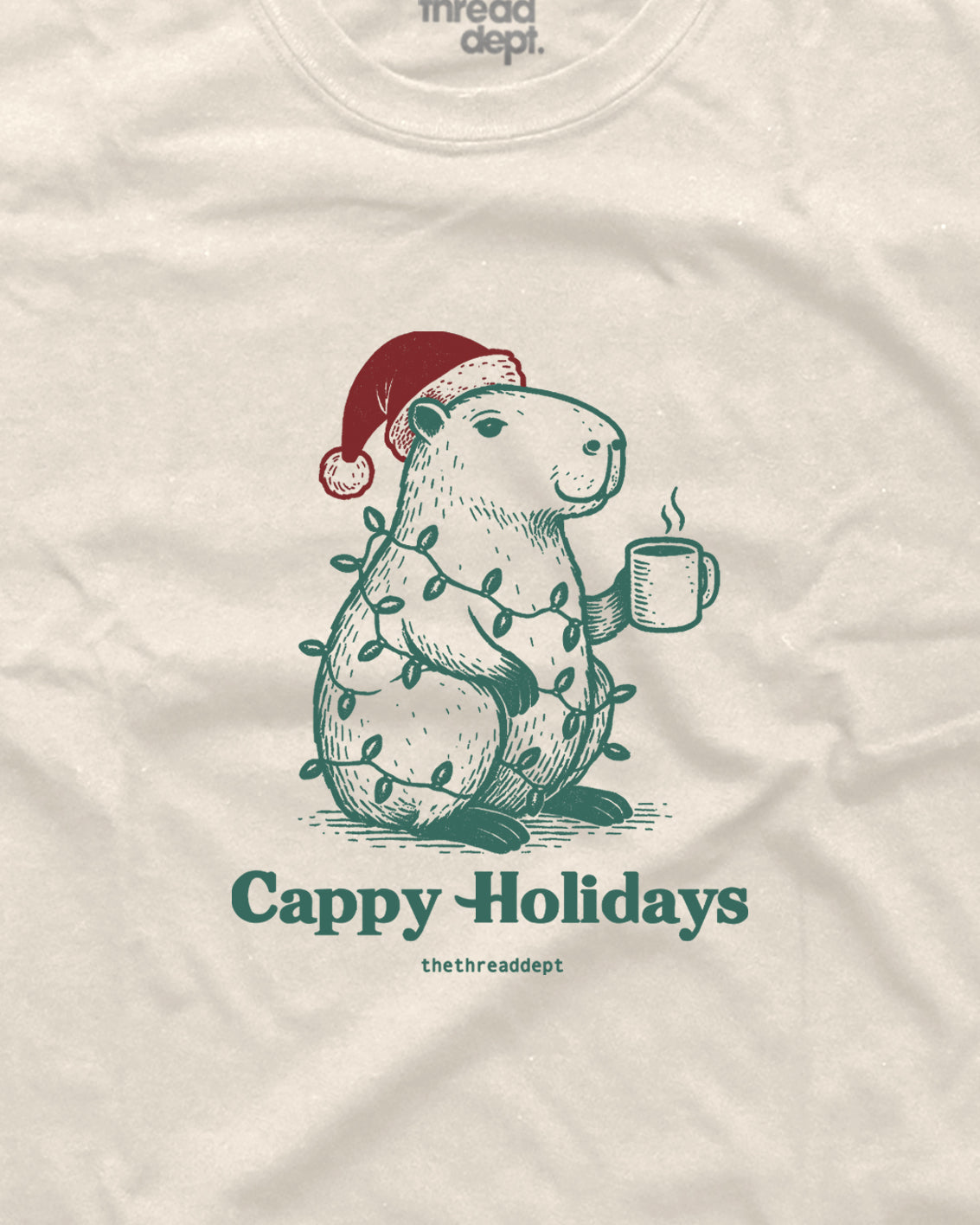 T-shirt with a design of a groundhog wearing a Santa hat and holding a mug, with 'Cappy Holidays' text and 'thread dept.' branding.