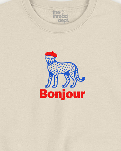 Beige t-shirt with a blue cheetah wearing a red hat and 'Bonjour' text on a beige background.