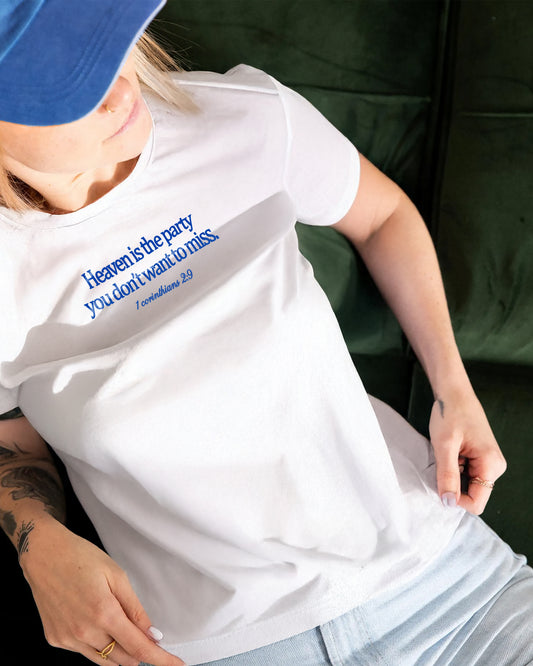 White t-shirt with blue text 'Heaven is the party you don't want to miss. 1 Corinthians 2:9' on a white graphic tee.