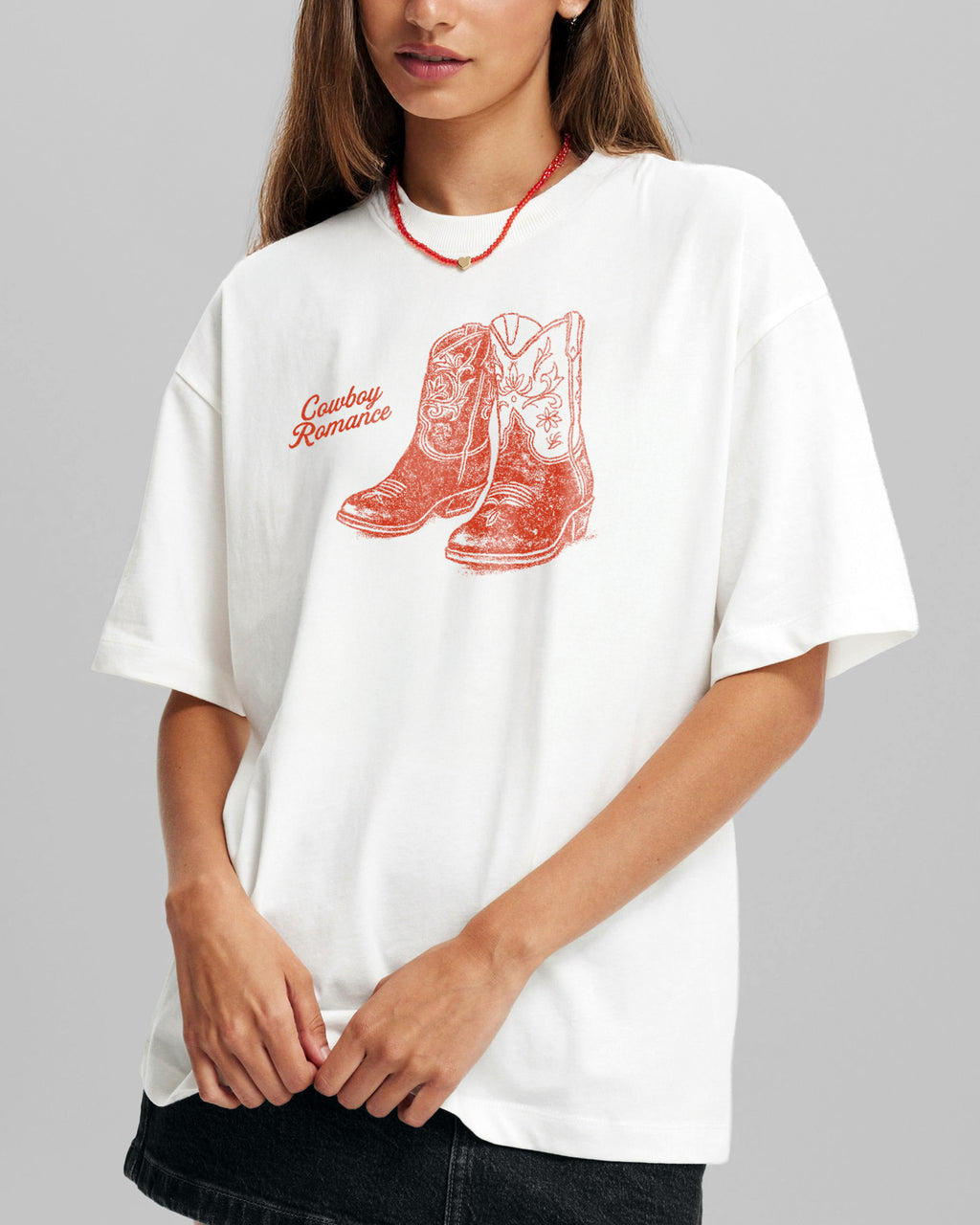 Person wearing a white t-shirt with red cowboy boot design and text on a gray background