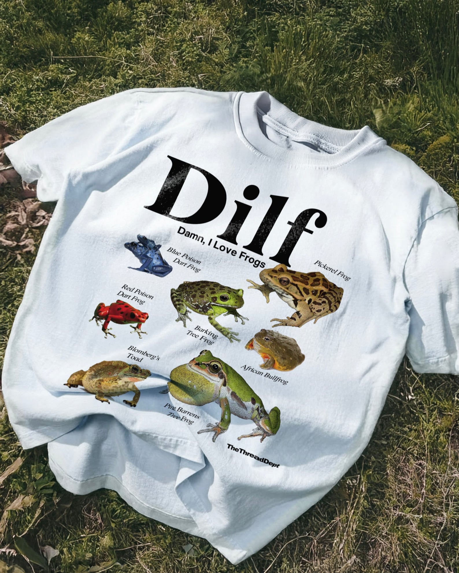 White t-shirt with 'Dilf, Damn I Love Frogs' and frog illustrations on grass