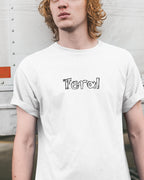 Person wearing a white t-shirt with 'Feral' printed on it against a plain background
