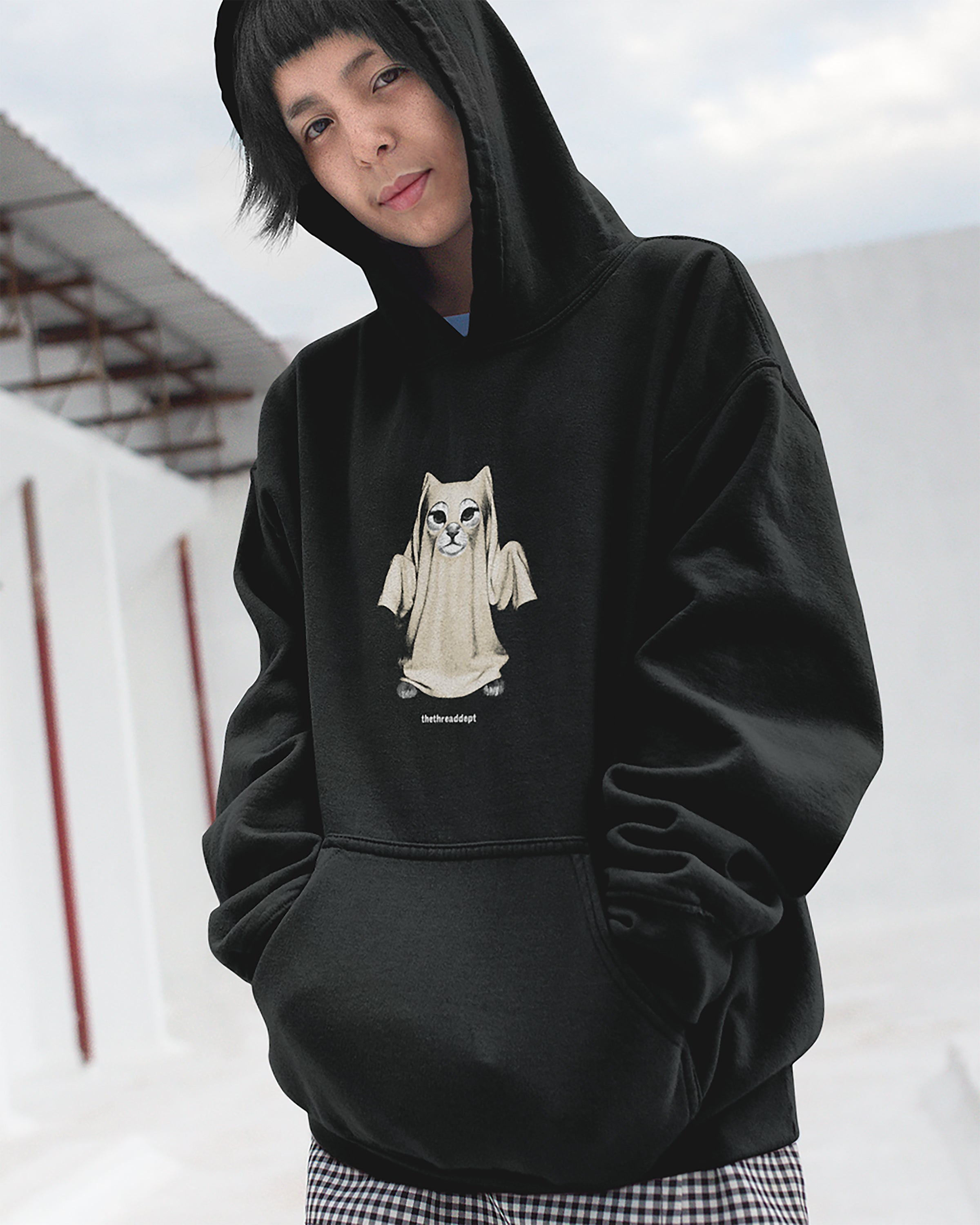 Person wearing a black hoodie with a graphic design of a cat-like creature on a white background.