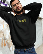 Man wearing a black sweatshirt with 'Hangry' text, standing against a wall.