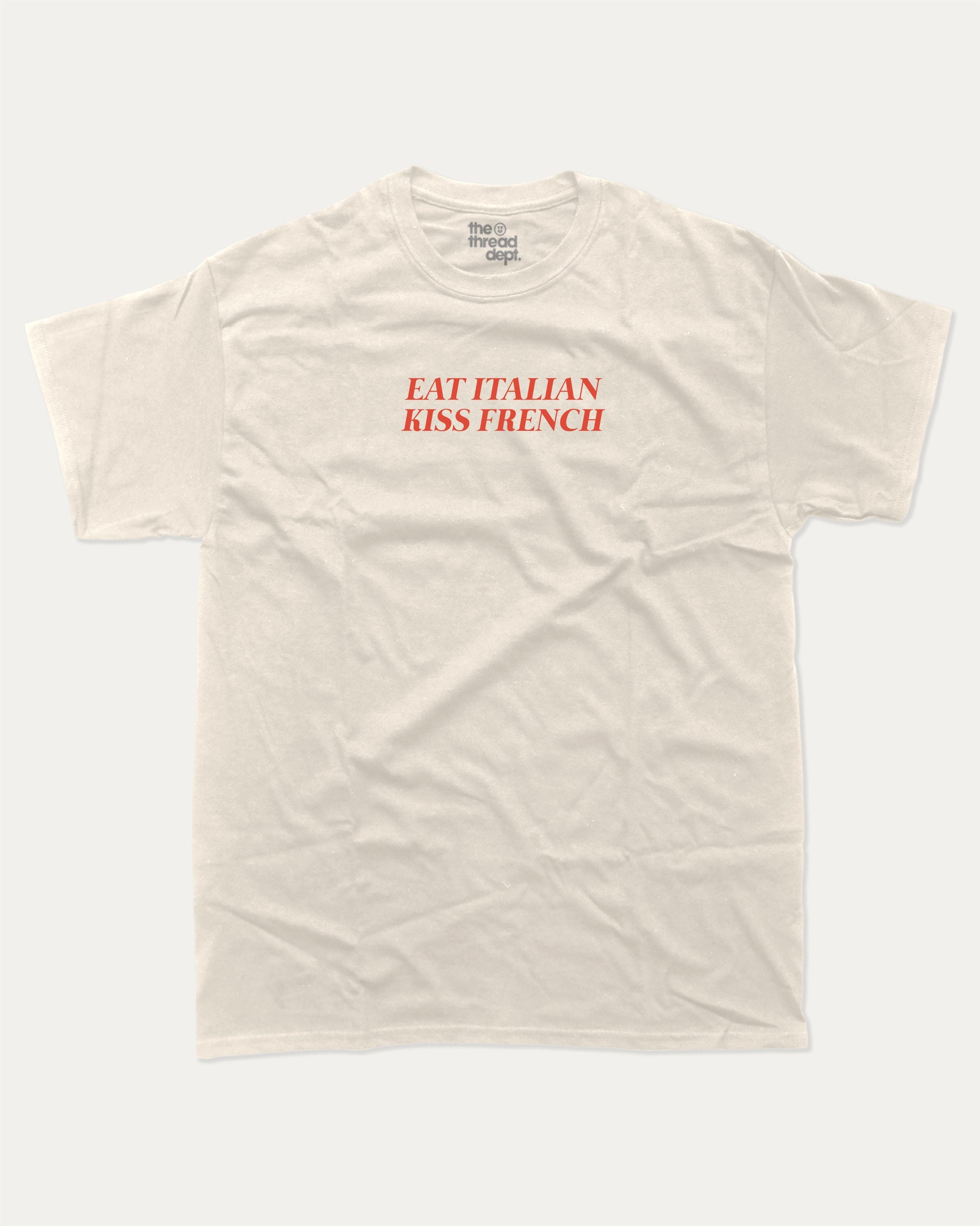 Eat Italian Kiss French graphic tee with bold and humorous print, funny and trendy graphic. Perfect for adults and gift-giving. Cream shirt.