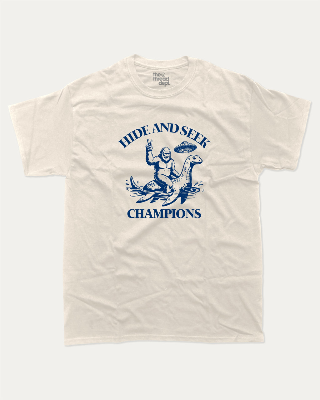 Hide and Seek Champions bigfoot graphic tee with retro and funny print, vintage and trendy graphic. Perfect funny gifts for friends and gift-giving. Cream shirt.