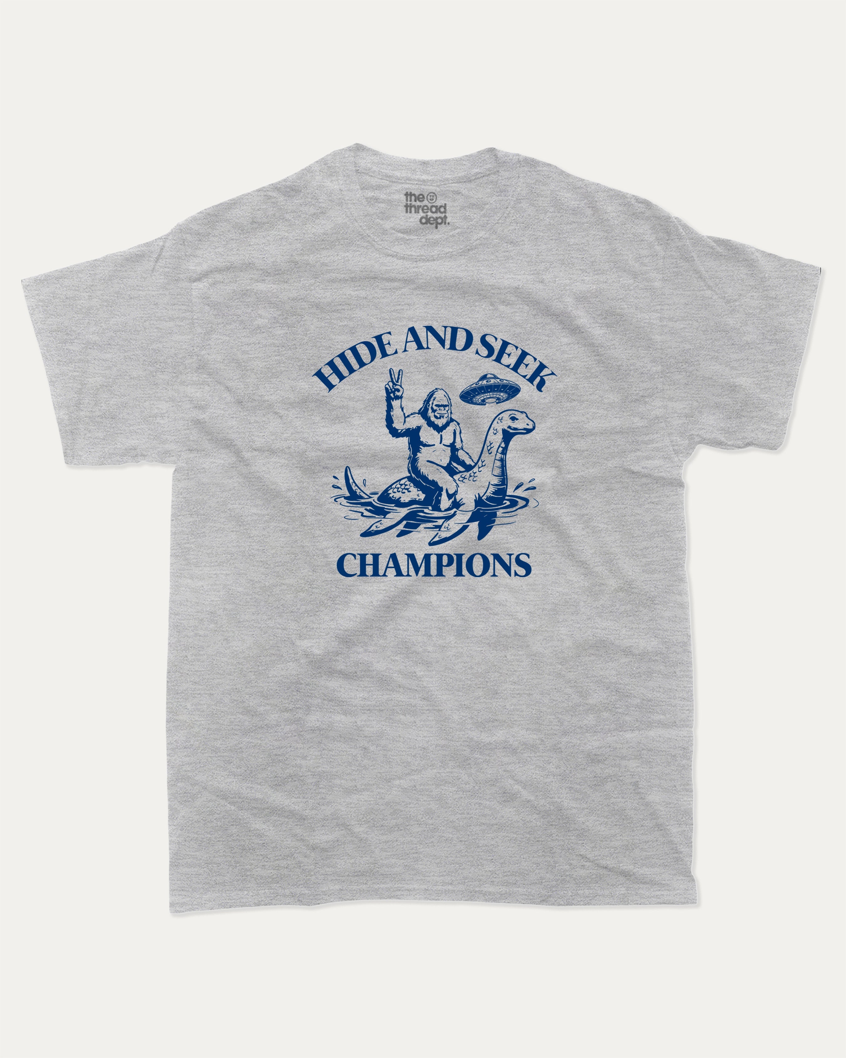 Hide and Seek Champions bigfoot graphic tee with retro and funny print, vintage and trendy graphic. Perfect funny gifts for friends and gift-giving. Heather Grey shirt.
