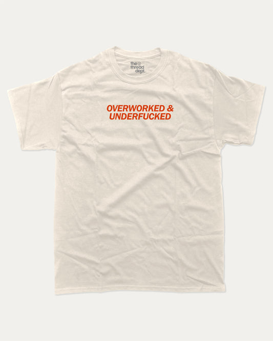 Overworked and Underfucked graphic tee with bold and humorous print, funny and trendy graphic. Perfect for adults and gift-giving. Cream shirt.
