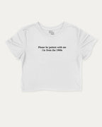 Please Be Patient With Me I'm From The 1900s graphic crop tee with funny and retro slogan print, perfect for women_ casual looks or layering. White crop t-shirt.