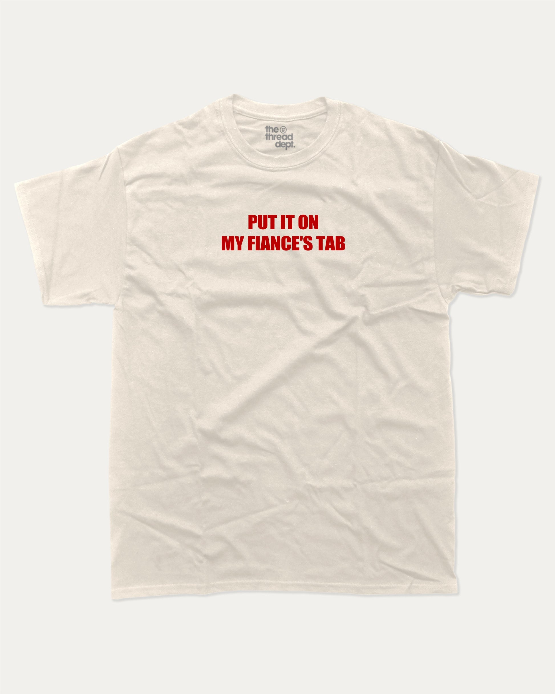 Put It On My Fiance's Tab graphic tee with bold and humorous print, funny and trendy graphic. Perfect for adults and gift-giving. Cream shirt.