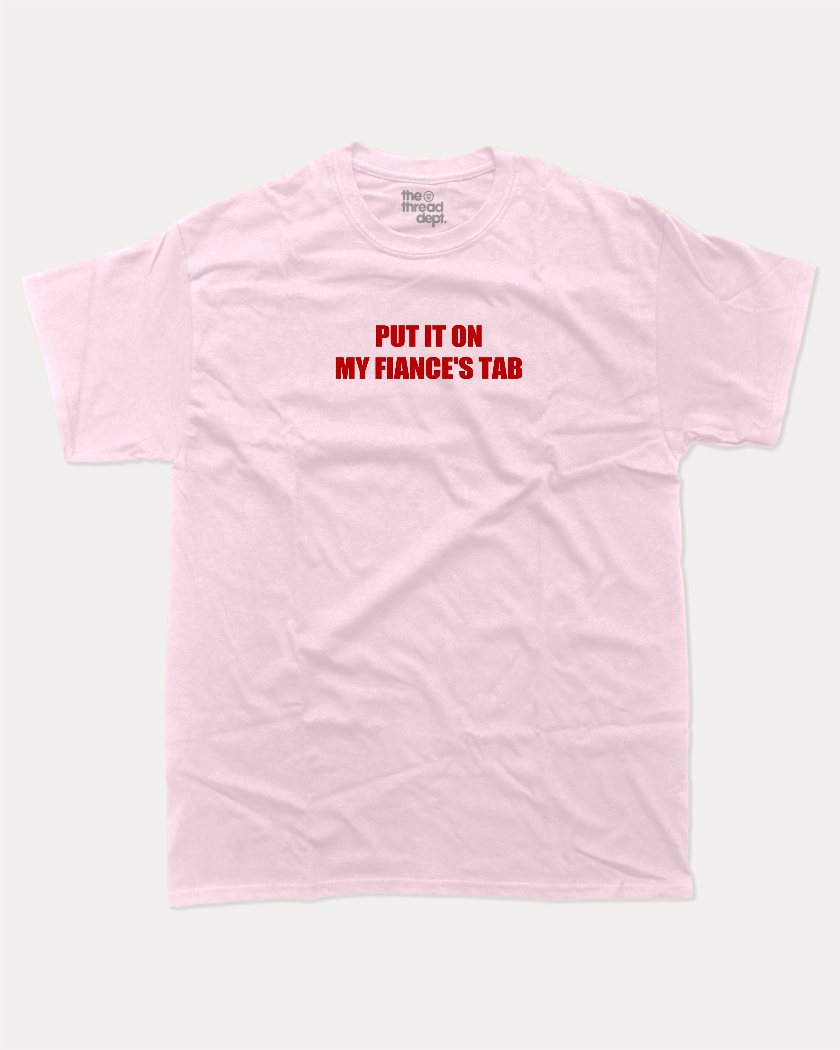 Put It On My Fiance's Tab graphic tee with bold and humorous print, funny and trendy graphic. Perfect for adults and gift-giving. Pink shirt.