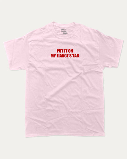 Put It On My Fiance's Tab graphic tee with bold and humorous print, funny and trendy graphic. Perfect for adults and gift-giving. Pink shirt.
