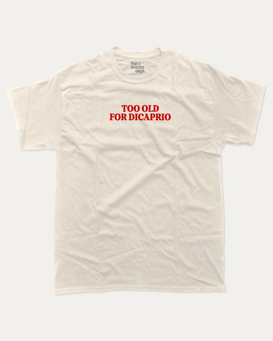 Too Old For Dicaprio graphic tee with bold and humorous print, funny and trendy graphic. Perfect for adults and gift-giving. Cream shirt.