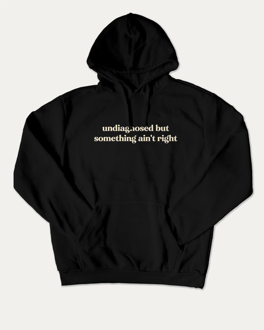 Undiagnosed But Something Ain't Right bold graphic hoodie, perfect for adults. A must-have graphic hoodie, cozy and cool, trending streetwear essential. Black hoodie