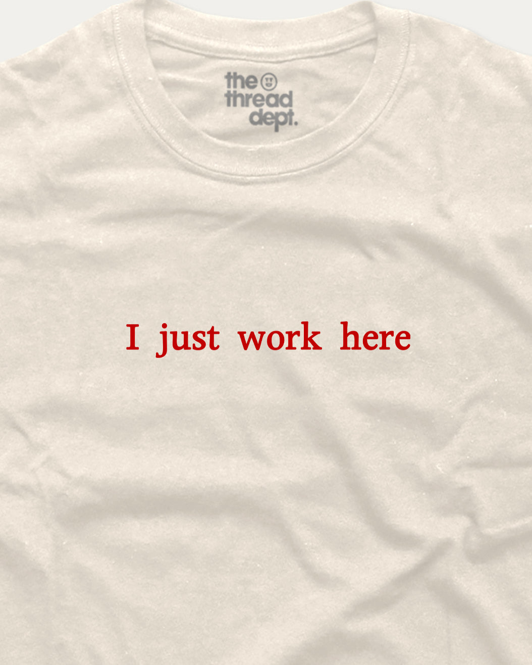 White t-shirt with red text 'I just work here' and 'the thread dept.' logo on a white background