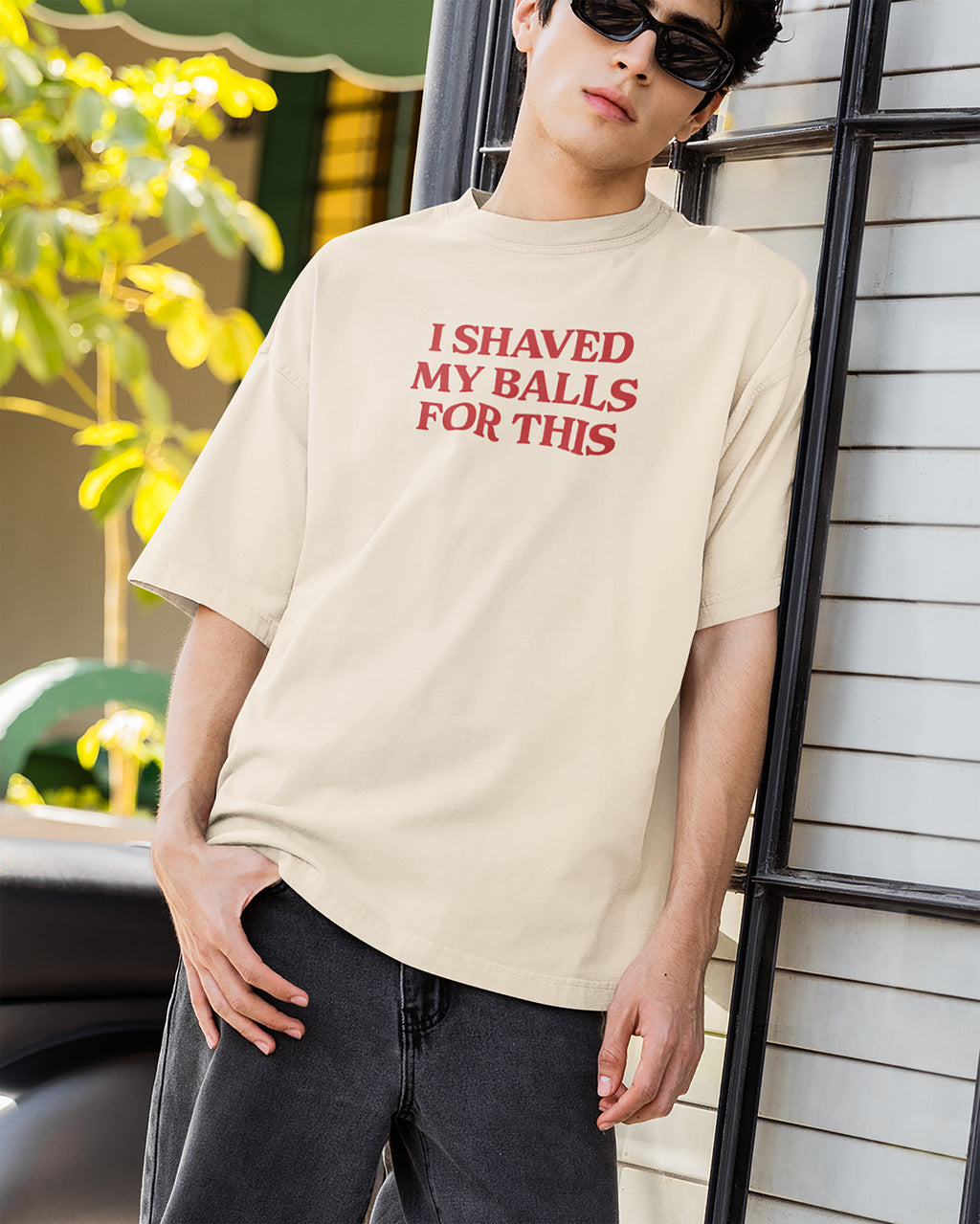 Person wearing a beige t-shirt with red text outdoors.