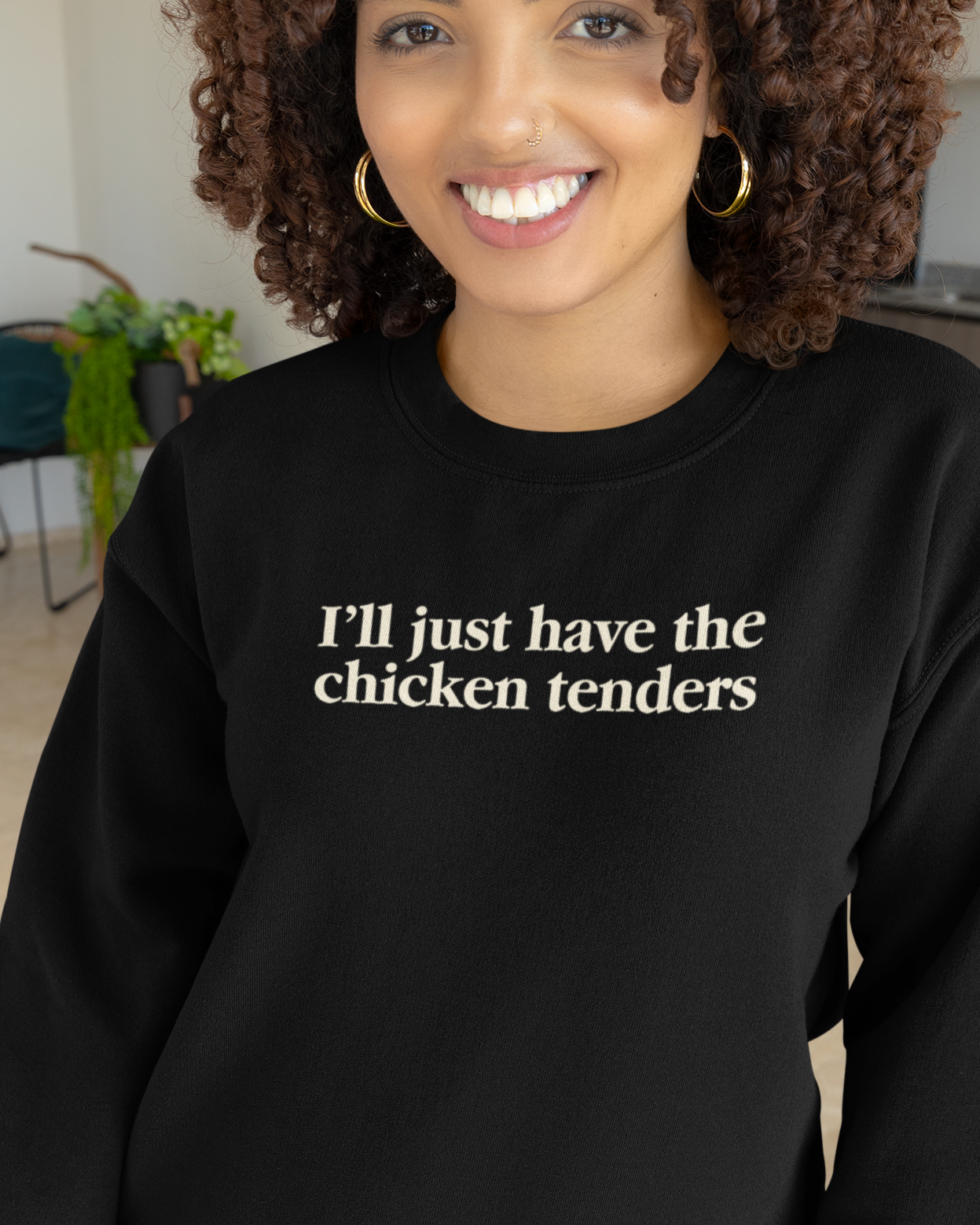 Person wearing a black sweatshirt with text, standing indoors.