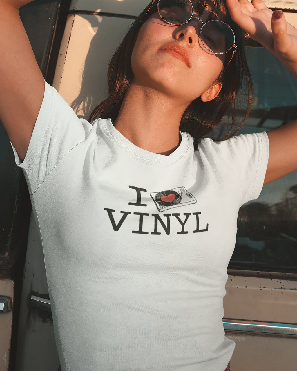 Person wearing a white t-shirt with 'I  Love VINYL' design, standing next to a car.