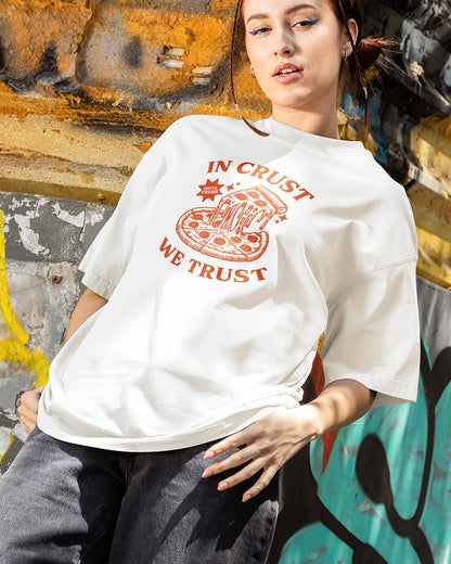 Person wearing a white t-shirt with a pizza graphic and text against a graffiti-covered wall.