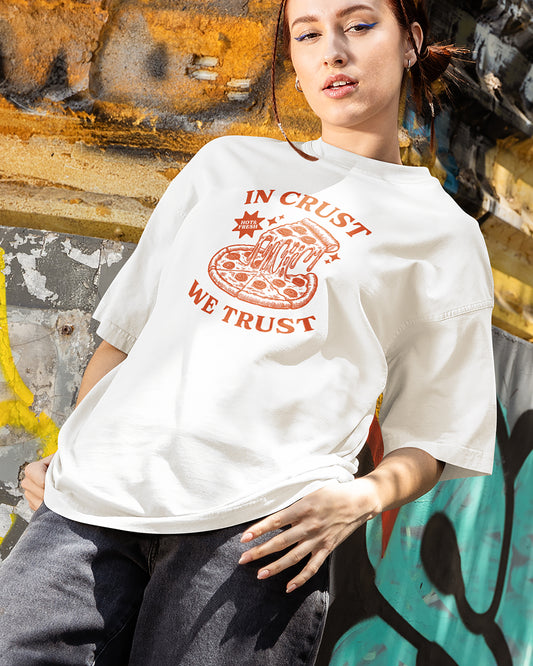 Person wearing a white t-shirt with a pizza graphic and text against a graffiti-covered wall.