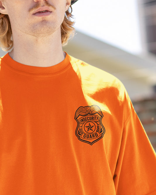 Person wearing an orange shirt with a security guard logo on a blurred background