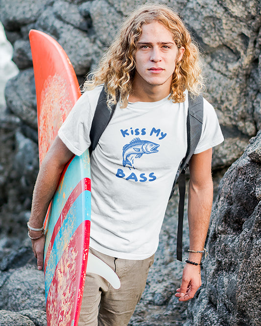 Person holding a surfboard with 'Kiss My Bass' t-shirt on rocky background