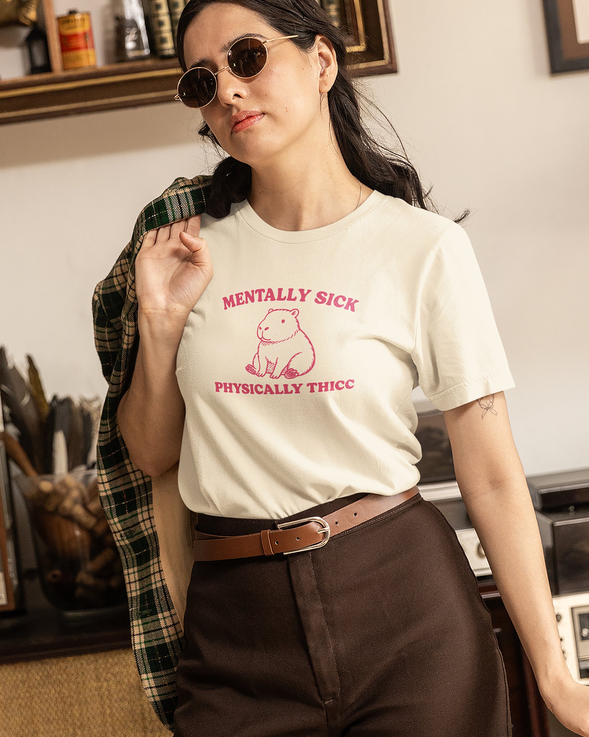 Person wearing a white t-shirt with pink text and graphics, standing in an indoor setting.
