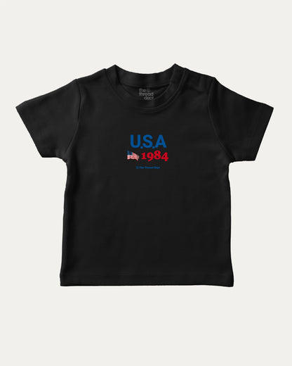 USA 1984 playful kids' graphic tee, perfect for boys and girls. A must-have fun shirt for school, playtime, or gifting. Black baby t-shirt