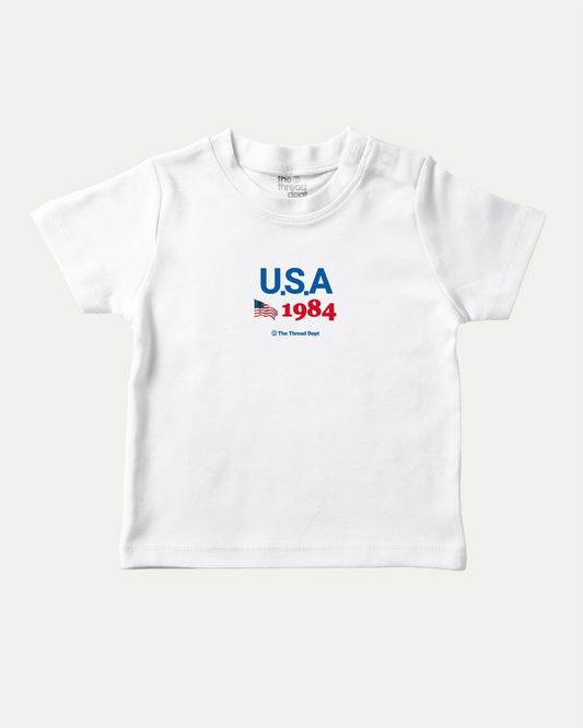 USA 1984 playful kids' graphic tee, perfect for boys and girls. A must-have fun shirt for school, playtime, or gifting. White baby t-shirt