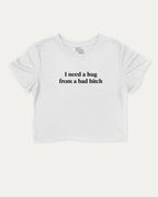 I Need A Hug From A Bad Bitch graphic crop tee with funny and trendy slogan print, perfect for women’s casual looks or layering. White crop t-shirt.