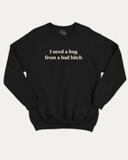 I Need A Hug From A Bad Bitch graphic sweatshirt with bold and funny print, warm and cozy graphic for everyday wear. Perfect for adults and gift-giving. Black pullover.