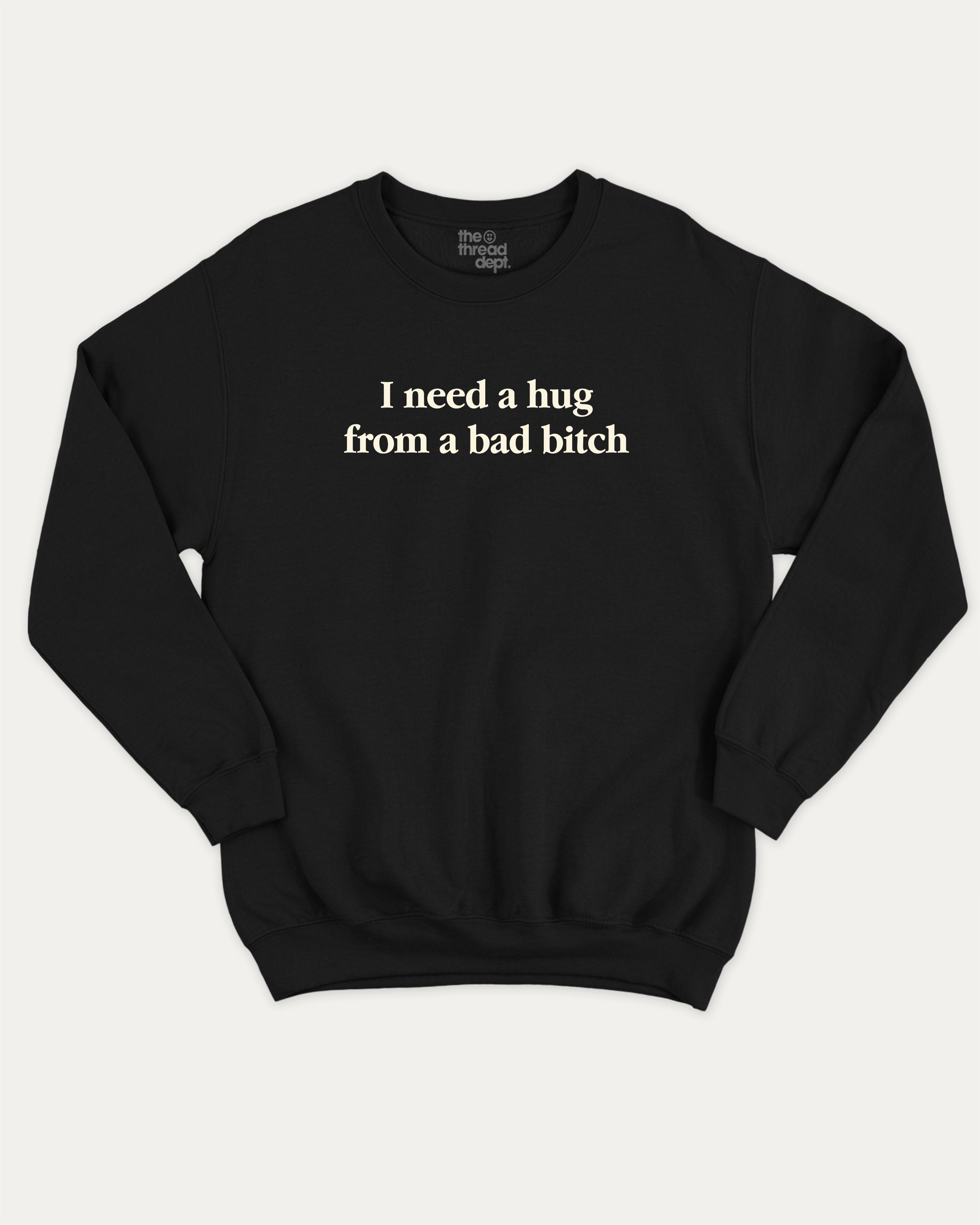 I Need A Hug From A Bad Bitch graphic sweatshirt with bold and funny print, warm and cozy graphic for everyday wear. Perfect for adults and gift-giving. Black pullover.