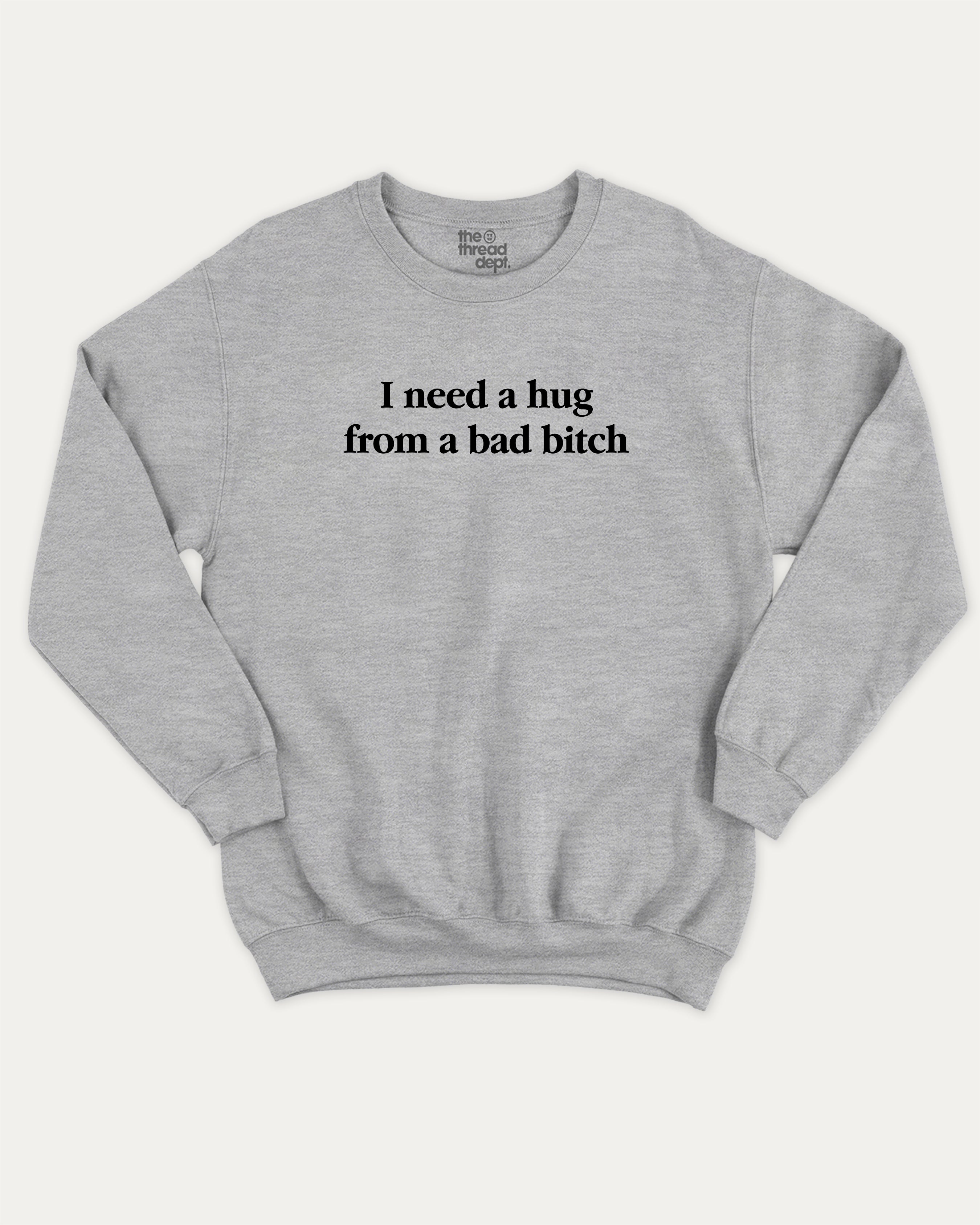 I Need A Hug From A Bad Bitch graphic sweatshirt with bold and funny print, warm and cozy graphic for everyday wear. Perfect for adults and gift-giving. Heather Grey pullover.