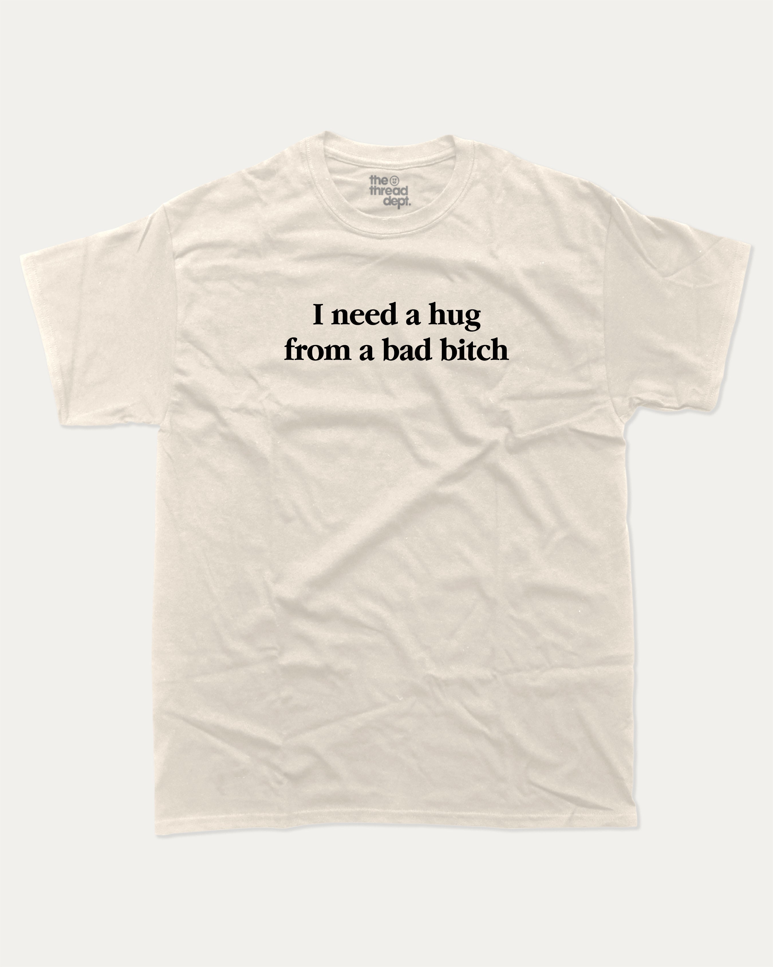 I Need A Hug From A Bad Bitch graphic tee with bold and funny print, funny and trendy graphic. Perfect for adults and gift-giving. Cream shirt.