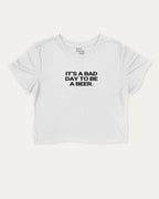 It's A Bad Day To Be A Beer graphic crop tee with funny and trendy sports print, perfect for women_ casual looks or layering. White crop t-shirt.